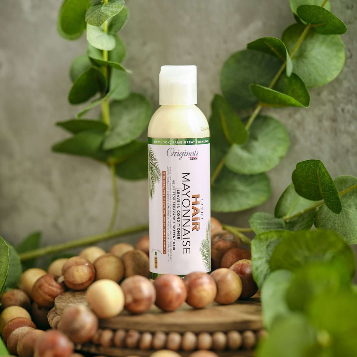 Africa's Best Originals Leave-In Conditioner bottle surrounded by greenery and wooden beads, showcasing its nourishing formula.